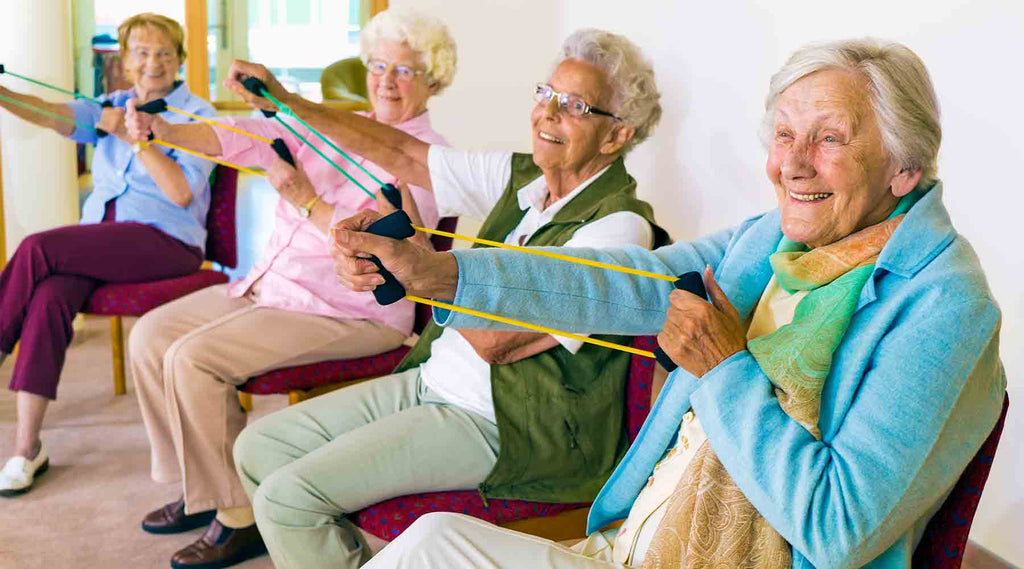 Elderly Women with Dementia doing seated exercises with resistance bands in a senior citizens center
